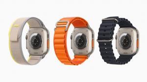 Three Apple Watch Ultra devices are shown from behind to feature their three different bands, including a gray-and-yellow Trail Loop, orange Alpine Loop, and black Ocean Band.  