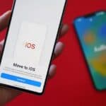 Hand holding a phone that says Move to iOS, with another phone in the background  