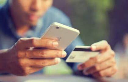 Closeup of a man's hands holding an iPhone and a credit card.  