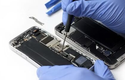 Closeup of technician's gloved hands repairing an iPhone's internal parts.  