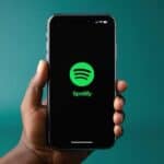 man holding an iPhone with spotify logo on screen