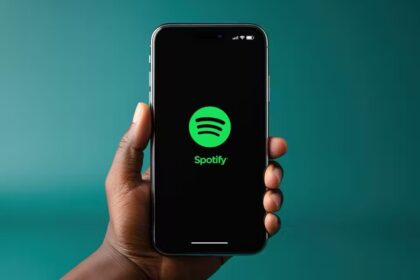 man holding an iPhone with spotify logo on screen