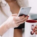 Woman holding iPhone and mug  