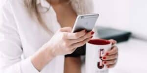 Woman holding iPhone and mug  