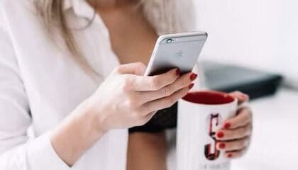 Woman holding iPhone and mug  