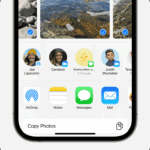 An iPhone showing the share sheet with photos selected and the AirDrop option displayed.  