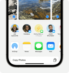 An iPhone showing the share sheet with photos selected and the AirDrop option displayed.  