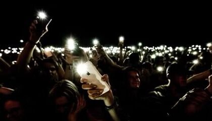 crowd holding iphone with flashlight in the dark  