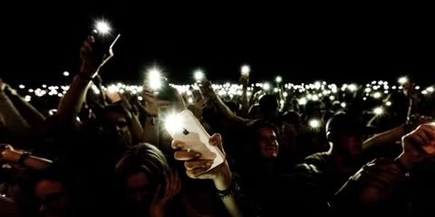 crowd holding iphone with flashlight in the dark  