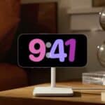 An iPhone on a nightstand with StandBy mode on, featuring a colorful clock
