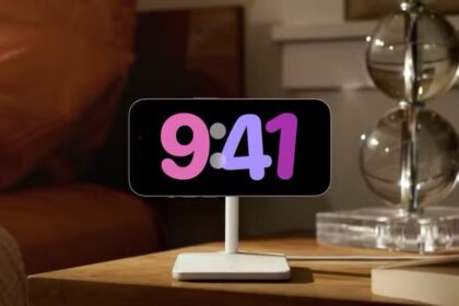An iPhone on a nightstand with StandBy mode on, featuring a colorful clock