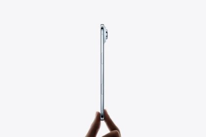 Hand holds iPhone Air from the bottom with fingertips, very thin side profile, titanium side exterior, Side button, Camera Control button, raised camera lens, sky blue color  