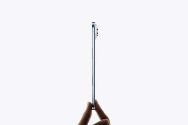 Hand holds iPhone Air from the bottom with fingertips, very thin side profile, titanium side exterior, Side button, Camera Control button, raised camera lens, sky blue color  
