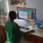 A Mac mini user works at a desk surrounded by ceramics pieces.