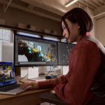 A person uses Studio Display XDR and MacBook Pro in an office-like setting.