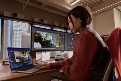 A person uses Studio Display XDR and MacBook Pro in an office-like setting.