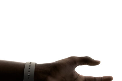 A hand wearing Apple Watch, with the thumb and index finger ready to make the double tap gesture.