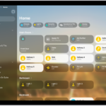 The Home app with the sidebar on the left, showing Home, Automation, and Discover tabs near the top left. Categories and Rooms in the home appear below. To the right of the sidebar, at the top, are the Intercom, Add, and More Options buttons. Category buttons appear near the top. Below that are scenes, camera images, and a room with its accessories.